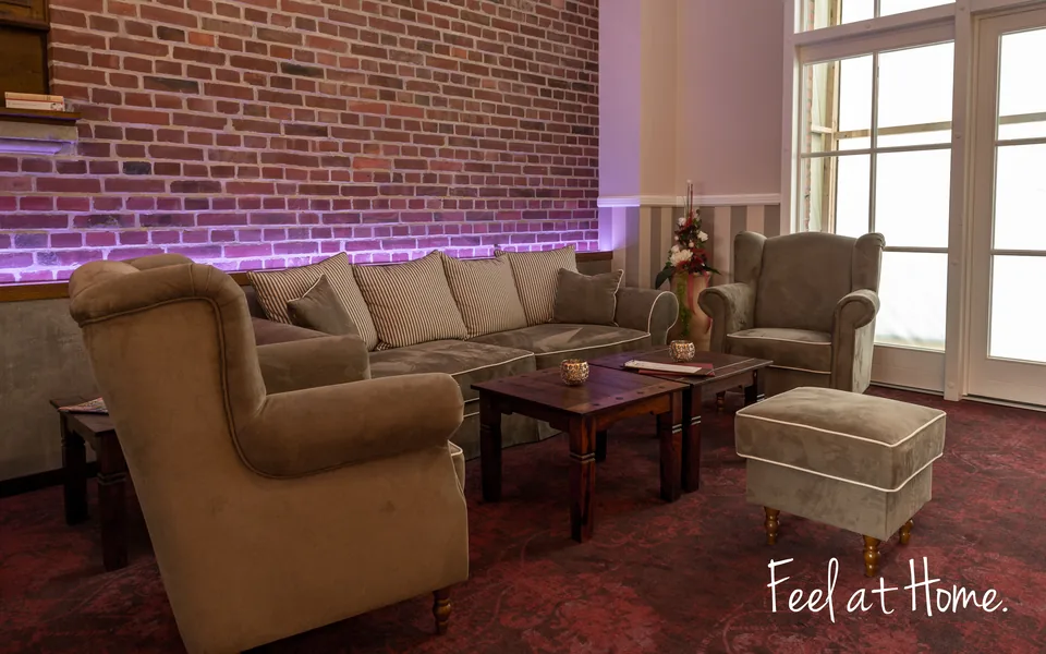Lounge mit Ohrensesseln und Backsteinwand