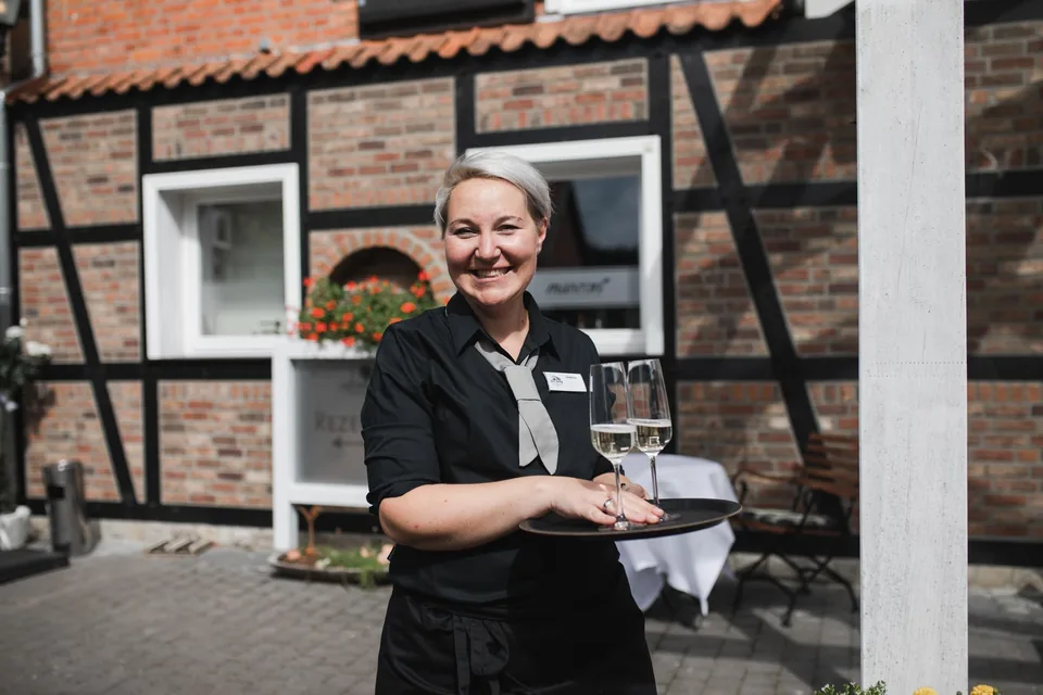 Eine Mitarbeiterin serviert den Hochzeitsgästen im Innenhof Getränke